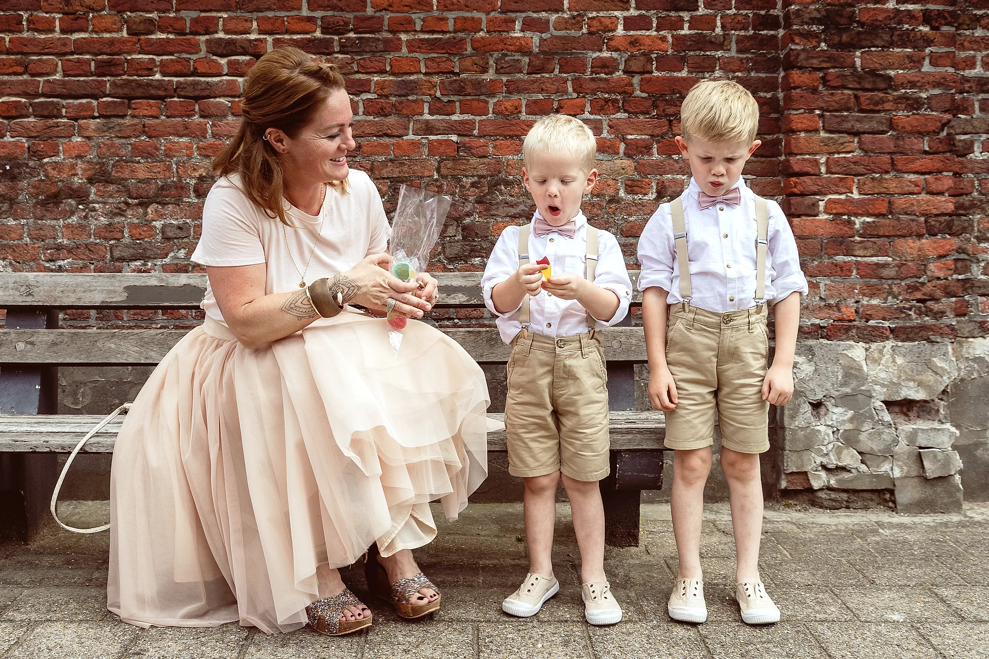 Mama met twee jongetjes op een bankje, snoep