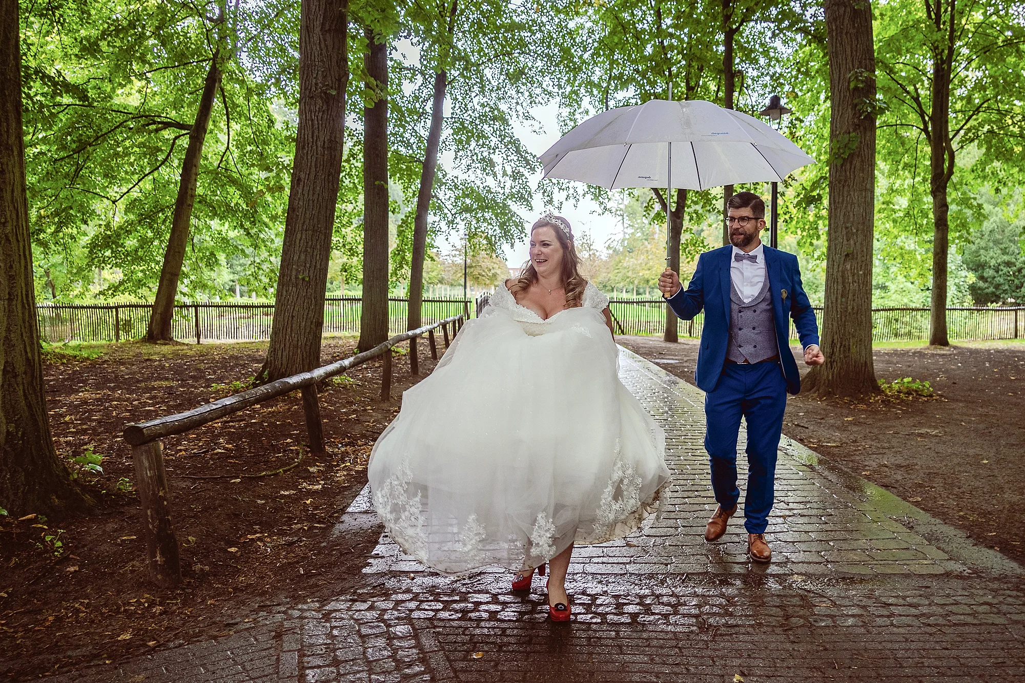 Bruid met rode hakken in de regen, paraplu-bruidegom