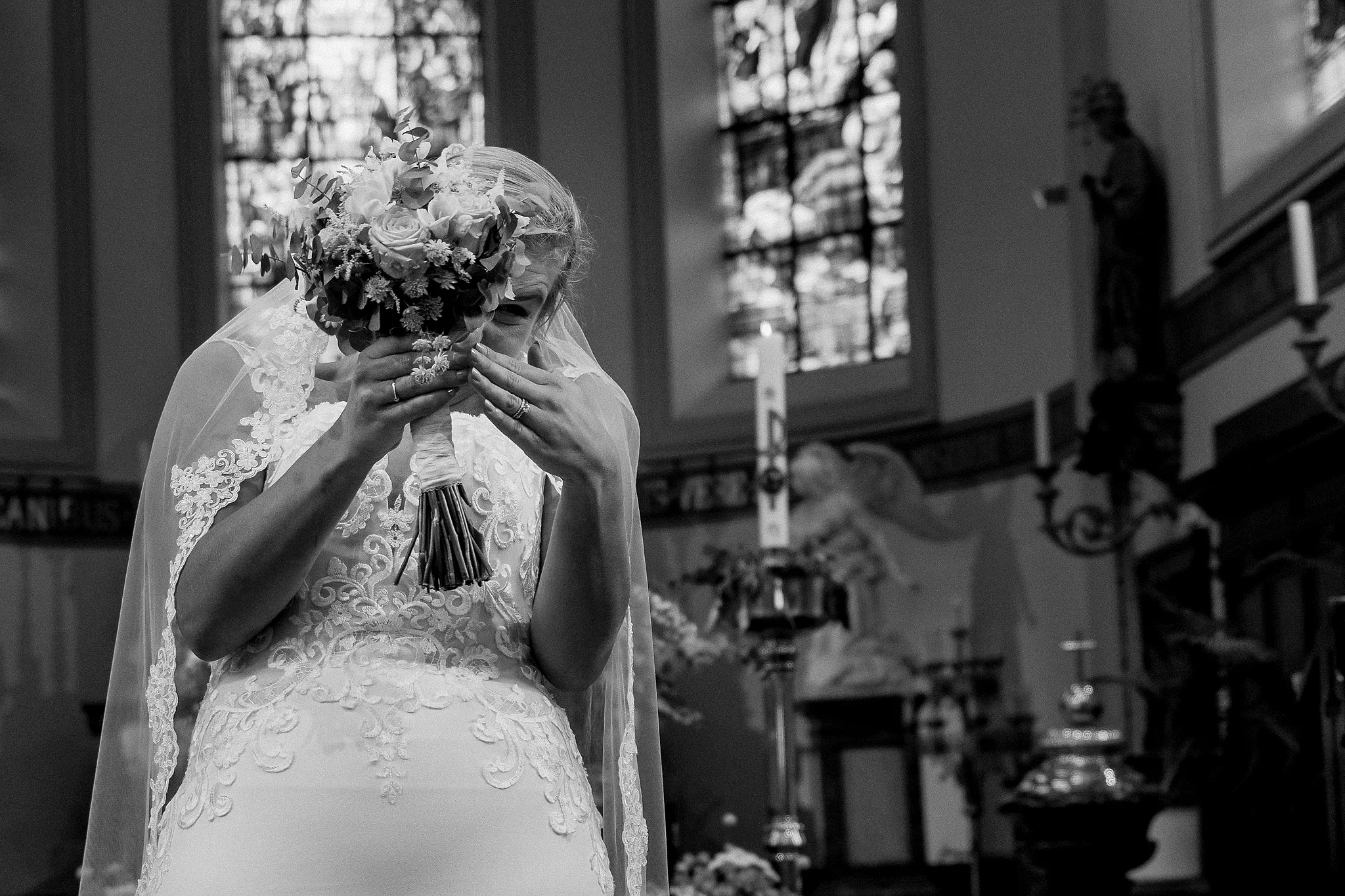 Bruid met boeket voor het gezicht in kerk