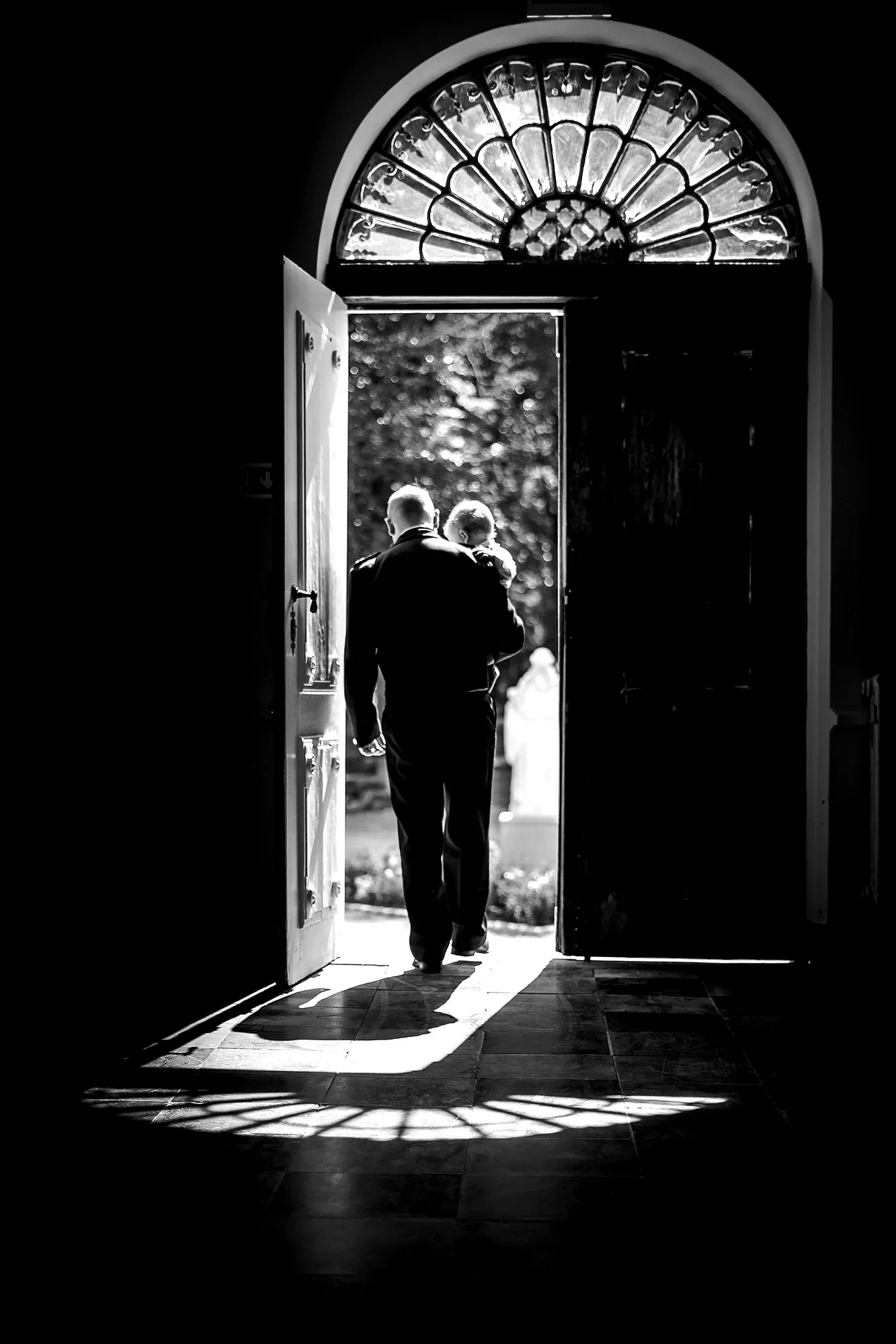 Father carries child through open church doors · vertical